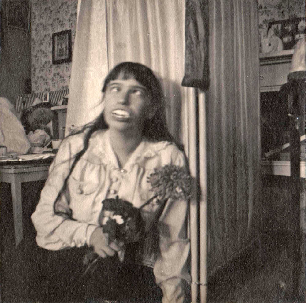 A young girl poses humorously for a photo with fake teeth