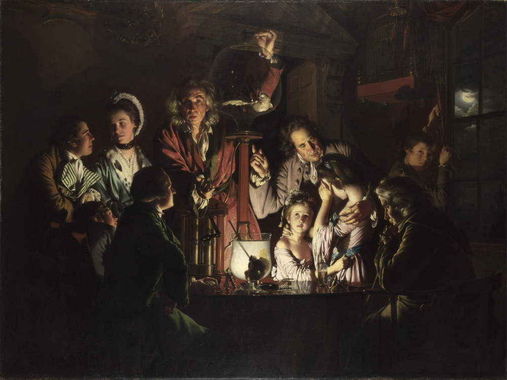 A group gathers round a table to witness an illuminating experiment