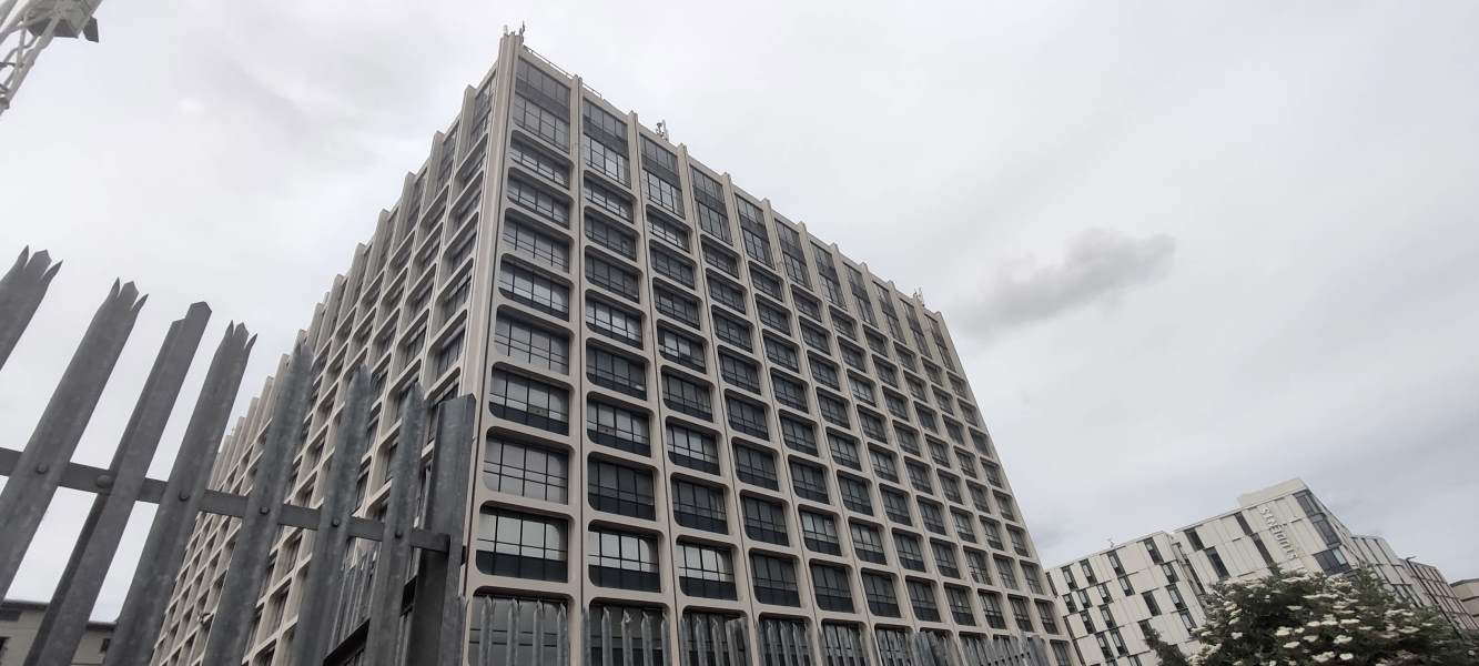 A hulking grey concrete building scrapes the sky.