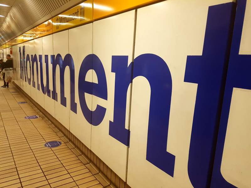 The giant label of Monument metro station stretches into the background.