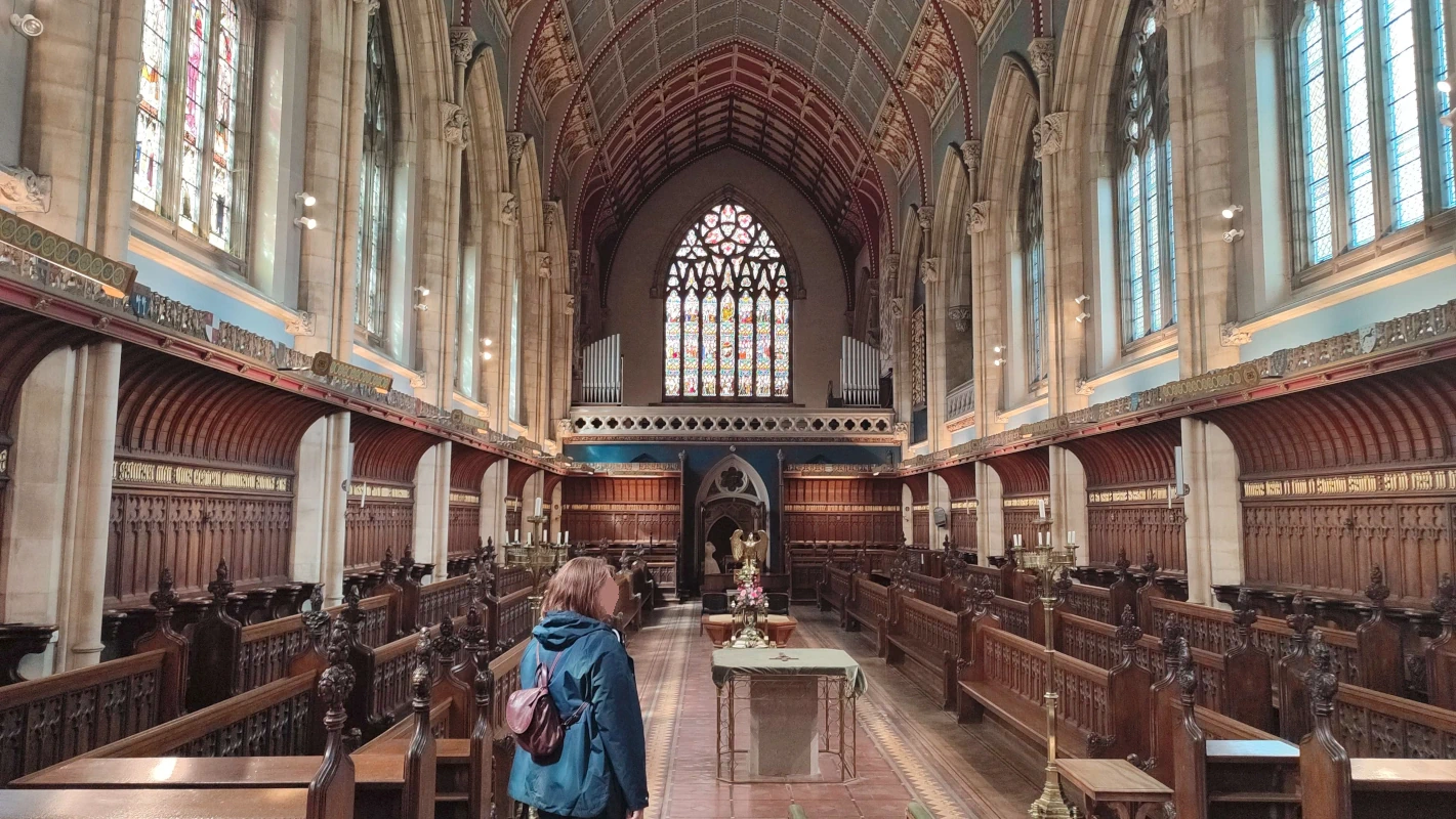 An ostentatiously-decorated main chapel, with intricate carved wooden benches and walls, painted ceilings, and stained glass windows